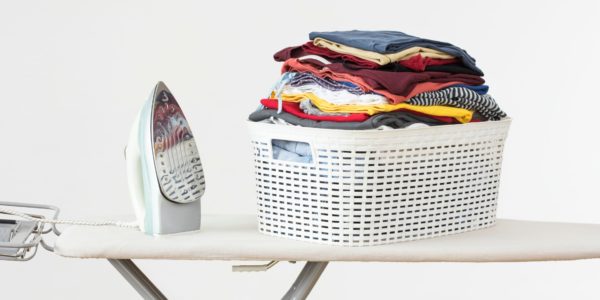 Fer à repasser et panière à linge sur une planche à repasser à Genève
