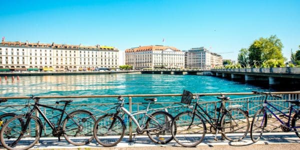 Vélo devant un quai au bord de l'eau avec bâtiments historiques à Genève.