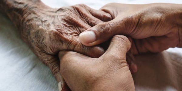 Un proche aidant tenant la main de l'aidé