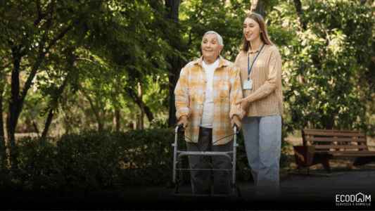 Une aide à domicile, marchant avec une sénior dans un parc
