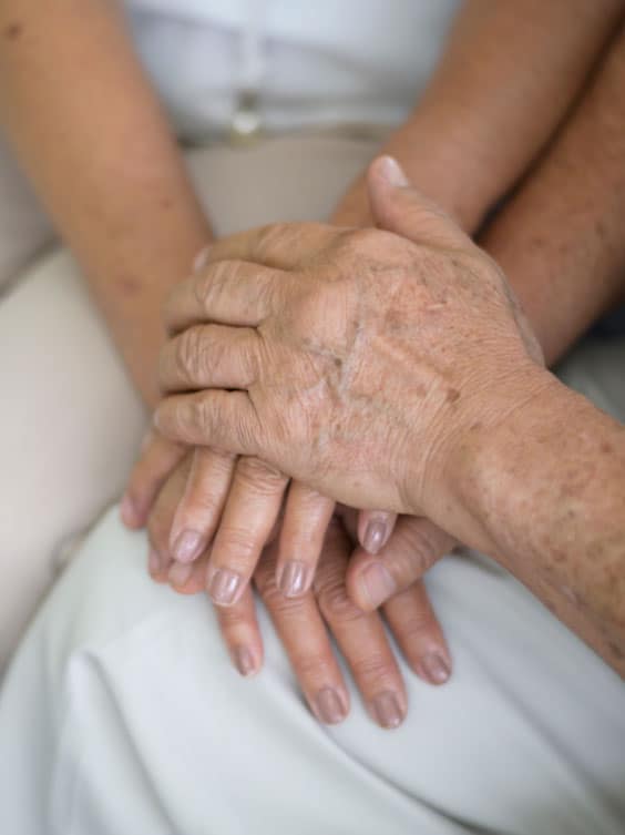 Une aide à domicile à Genève souriante, se promenant dans un parc avec une personne en situation de handicap.