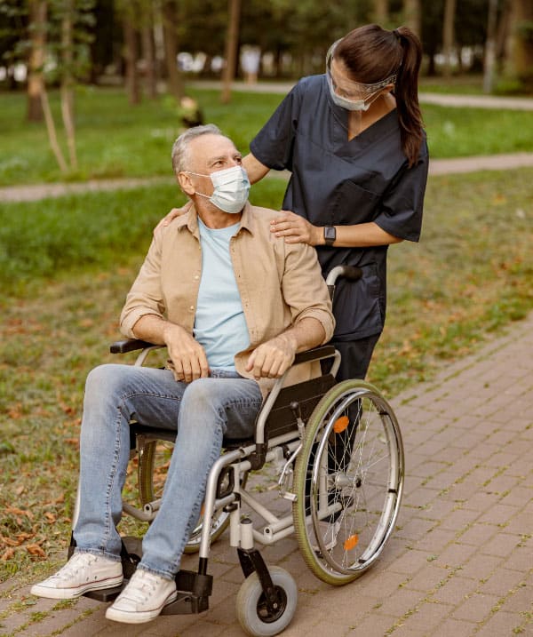 Une aide à domicile à Genève souriante, se promenant dans un parc avec une personne en situation de handicap.